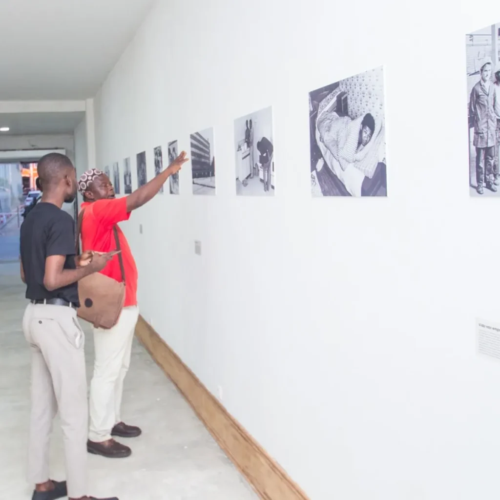 Zwei Besucher zeigen auf ein Foto an der Wand, Luanda 2023